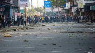 Massa demonstrasi memenuhi jalan depan gedung DPR RI pada 25 Agustus 2025, dengan sisa kericuhan dan batu berserakan di jalan.