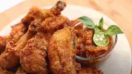 Potongan ayam goreng crispy disajikan dengan saus sambal dan jeruk limau