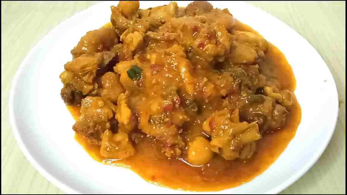 Rica-rica ayam pedas manis dengan bumbu merah gurih disajikan di atas piring putih.