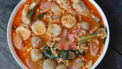 Mangkuk seblak kuah pedas khas Bandung dengan isian kerupuk aci, cilok, sosis, bakso, mi, ceker ayam, dan sayuran.