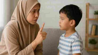 Ibu Muslim Indonesia sedang menegur anak laki-lakinya dengan lembut di ruang tamu.