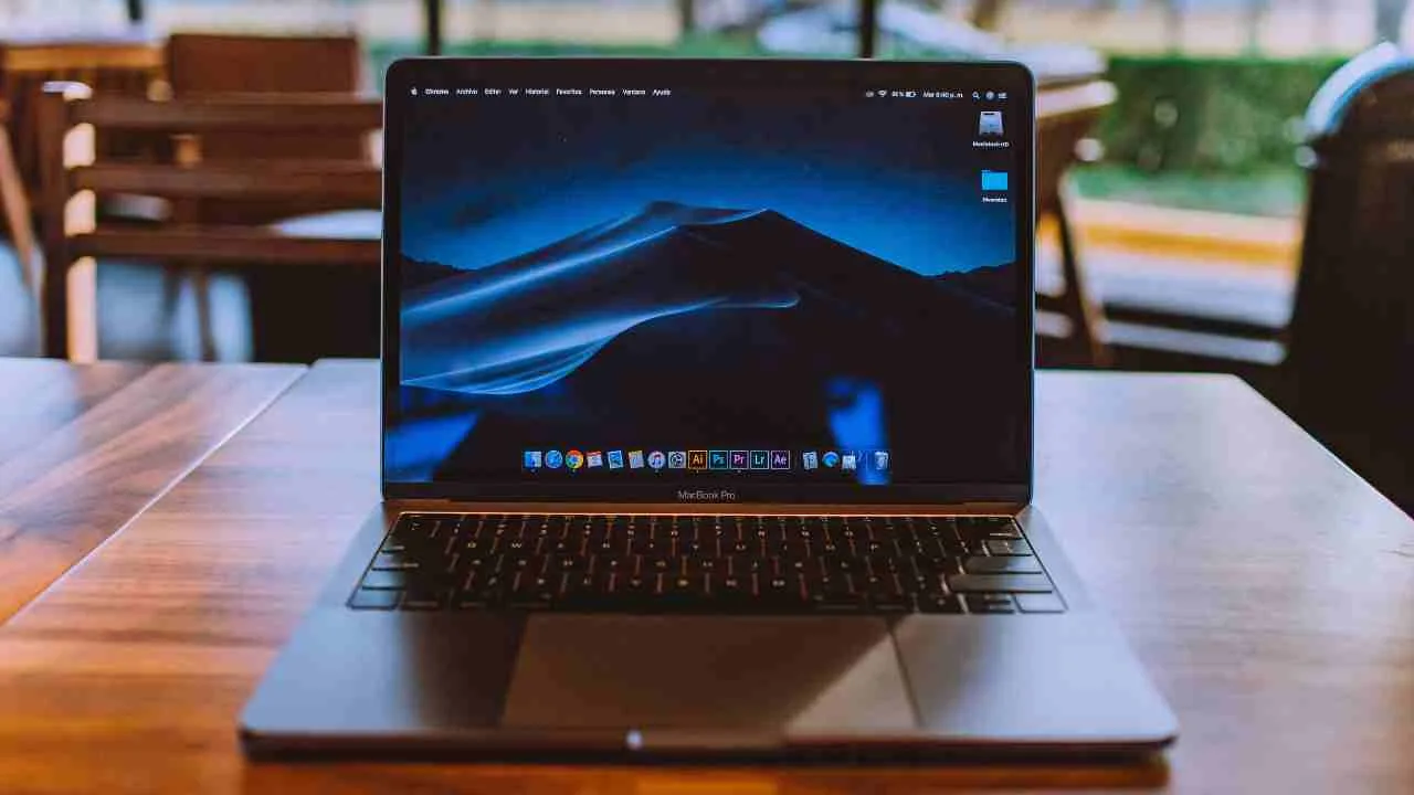 Laptop modern dengan layar menyala di atas meja kayu.