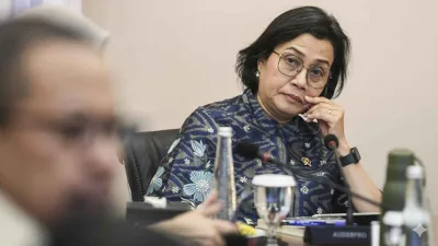 Sri Mulyani Indrawati saat menghadiri rapat, tampak serius mengenakan batik biru bermotif bunga.
