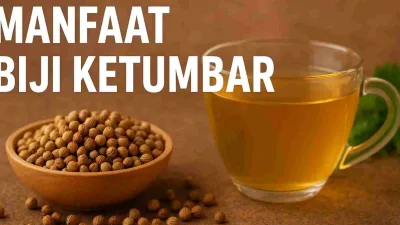 Segelas air rebusan biji ketumbar dan mangkuk kayu berisi biji ketumbar di atas meja cokelat.