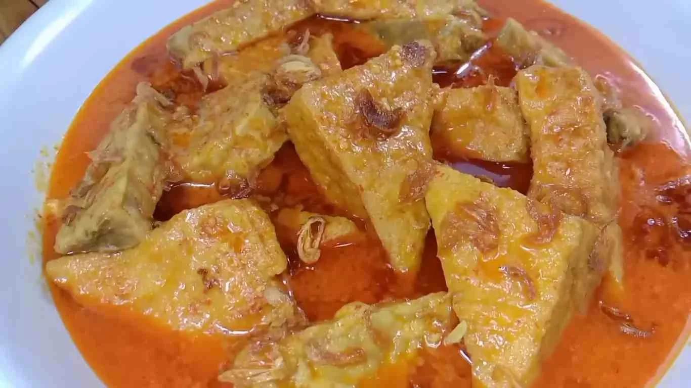 Sepiring gulai tempe tahu ala warteg dengan kuah santan kuning kemerahan yang gurih, disajikan dengan taburan bawang goreng di atasnya.