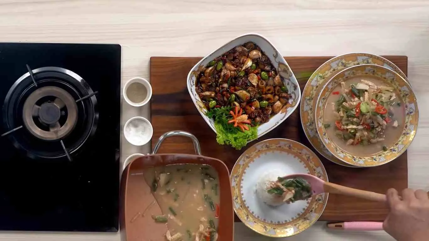 Proses penyajian lodeh tempe ndeso dan cumi asin pete di dapur rumahan.