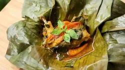 Pepes ayam kemangi dengan bumbu kuning dan daun kemangi segar disajikan dalam bungkus daun pisang.