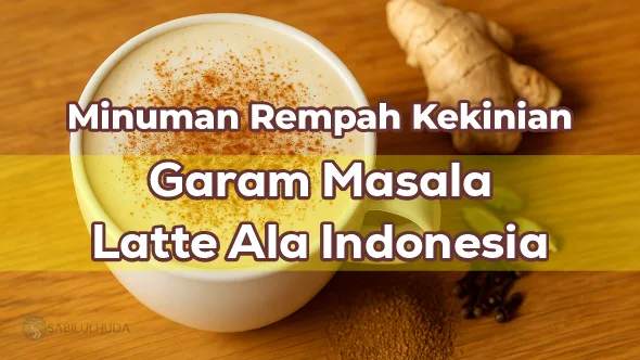 Secangkir Garam Masala Latte dengan busa susu lembut di atas meja kayu, di sampingnya terdapat bubuk rempah berwarna cokelat keemasan bersama jahe, kapulaga, dan cengkih.