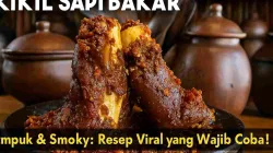 Kikil sapi bakar empuk dengan bumbu merah pedas mengilap, disajikan di atas piring hitam dengan latar dapur tradisional bernuansa gerabah.