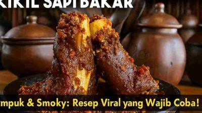 Kikil sapi bakar empuk dengan bumbu merah pedas mengilap, disajikan di atas piring hitam dengan latar dapur tradisional bernuansa gerabah.