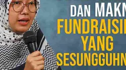 Diani Pratiwi berbicara dengan penuh semangat sambil memegang mikrofon, mengenakan hijab bermotif hitam putih, dengan latar belakang biru lembut dan tulisan besar berwarna putih dan kuning bertuliskan “Diani Pratiwi dan Makna Fundraising yang Sesungguhnya”.