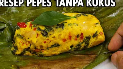 Pepes panggang tanpa kukus disajikan di atas daun pisang, berwarna kuning keemasan dengan potongan cabai merah dan daun kemangi yang tampak segar.