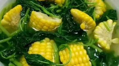 Semangkuk sayur bening bayam jagung manis dengan kuah jernih, berisi potongan jagung muda dan daun bayam segar.