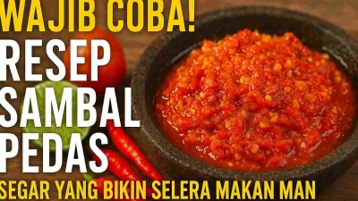 Sambal merah pedas dalam cobek batu dengan tekstur kasar dan minyak yang mengkilap, dikelilingi cabai merah, jeruk limau, dan tomat sebagai bahan utama.