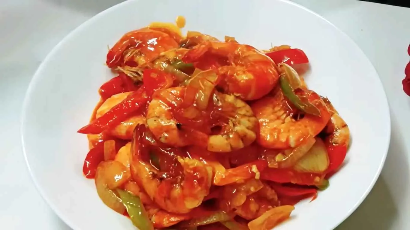 Udang asam manis dengan saus merah mengkilap disajikan di piring putih